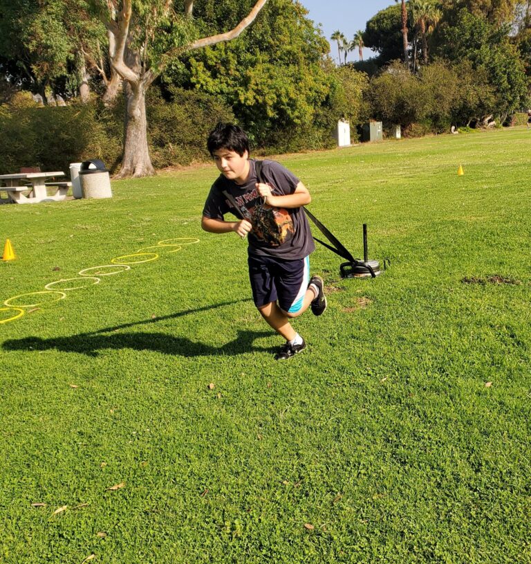 Youth athlete performing sled drag during outdoor strength training program in San Diego