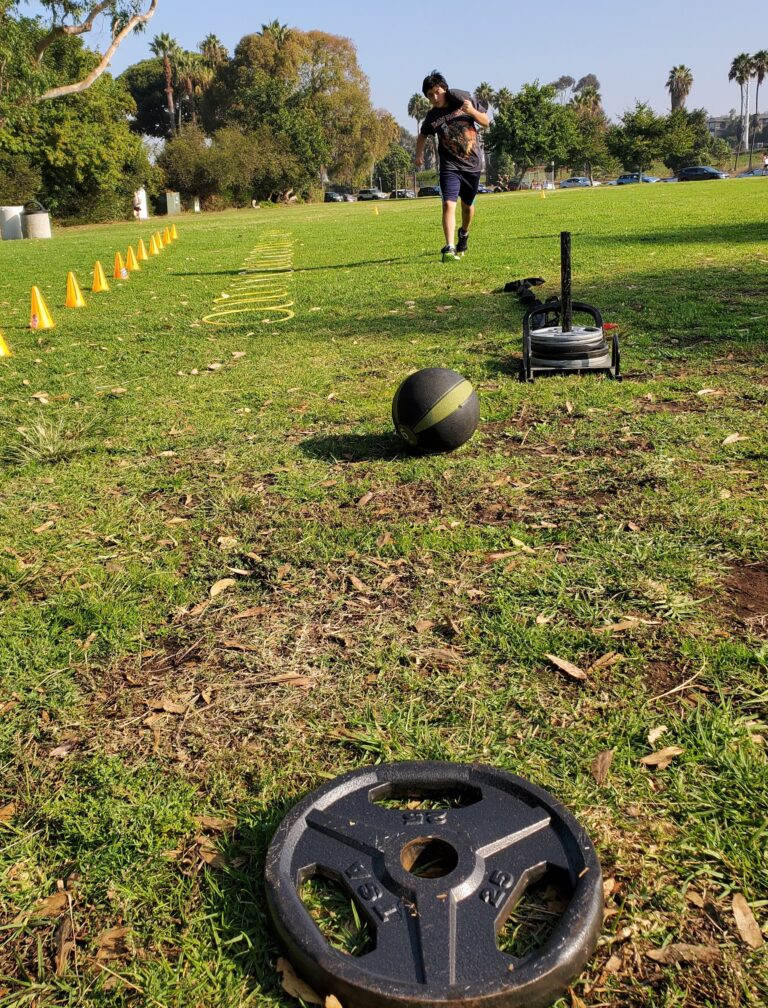 Structured outdoor youth fitness program session with training equipment at a San Diego park