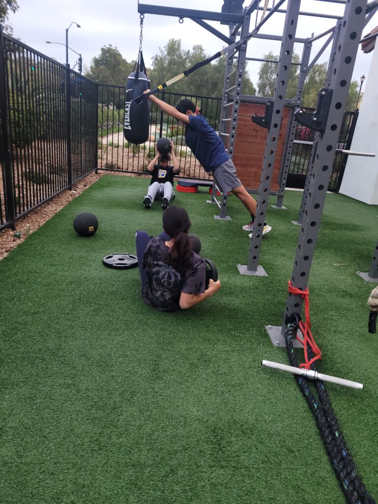 Youth athletes training in structured strength program with barbell rack and equipment in San Diego
